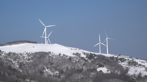 Wind-power-plants-are-seen-on-sky-background-in-the-snow-covered-mountain,-South-Korea