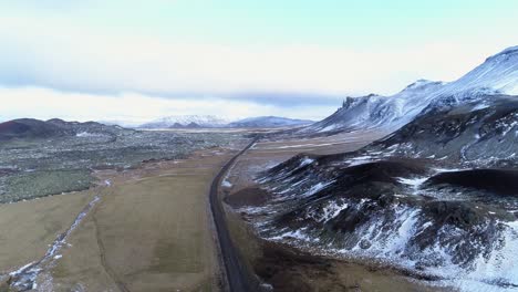 An-empty-wet-dirt-road-by-the-mountains-of-Phantom-Island-in-Iceland---aerial
