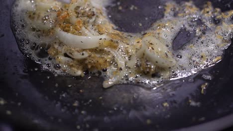 Minced-sizzling-garlic-sauteed-with-sliced-onions-in-black-fry-pan-with-white-spatula