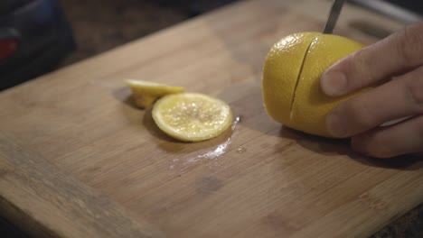 A-person-hands-slowly-cutting-a-fresh-lemon-on-a-cutting-board---Close-up-shot