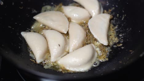 Pirogies-or-pelmeni-being-fryed-while-more-pirogies-are-being-thrown-into-hot-pan