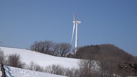 Un-Solo-Molino-De-Viento-Se-Está-Moviendo-Para-Generar-Electricidad,-Se-Ve-En-La-Montaña-Cubierta-De-Nieve,-Corea-Del-Sur