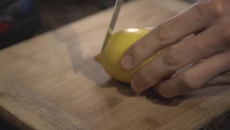 A-person-hands-cutting-slowly-a-fresh-ripped-lemon-on-a-cutting-board---Close-up-shot