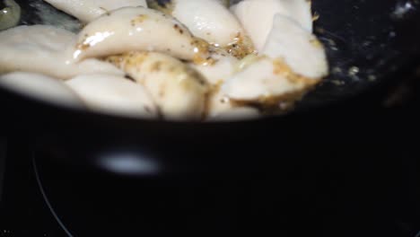 Slow-motion-large-dumplings-flipped-in-hot-pan-being-coated-with-herbs-and-oils