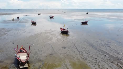 Traditional-fishing-boats-stuck-in-the-sand-during-low-tide-on-the-beaches-of-Thailand---aerial
