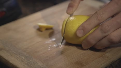 A-person-hands-slowly-cutting-a-fresh-lemon-on-a-wooden-board---Close-up-shot