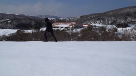 A-man-walks-on-clean-snow-in-windy-mountains,-snowy-hills-panorama-in-South-Korea