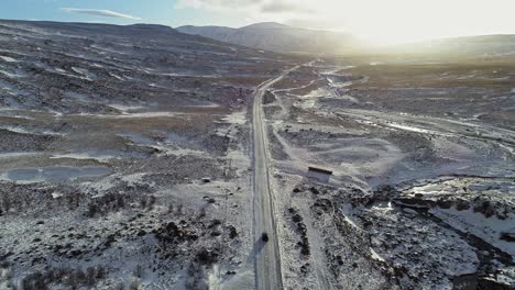 Un-Coche-Conduciendo-Lentamente-Por-La-Carretera-Resbaladiza-En-Islandia-Teniendo-Especial-Cuidado-Con-La-Nieve-En-Una-Mañana-Soleada-Y-Brillante---Toma-Aérea-De-Drones