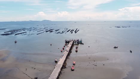 AERIAL,-Pier-And-Small-Boats-During-Low-Tide-At-Asian-Coastal-Beach
