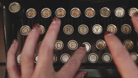 Close-up-top-down-shot-of-a-woman-typing-on-an-antique-typewriter