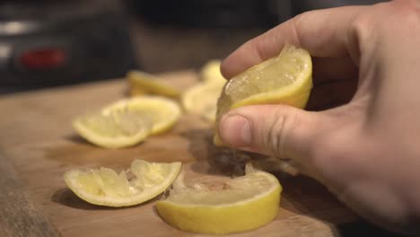 A-person-squeeze-the-lemon-on-a-wooden-board---Close-up-shot