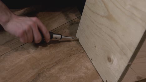 Human-hand-driving-screw-into-wooden-board---close-up-shot