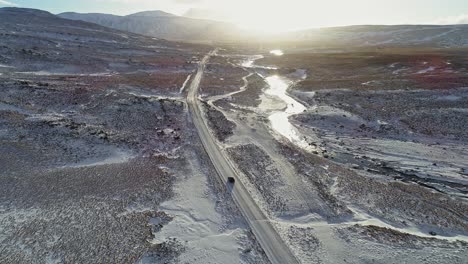 A-Car-Travelling-On-The-Snowy-Road-In-Iceland-With-The-Bright-Sun-In-The-Background-On-An-Early-Morning---Aerial-Drone-Shot