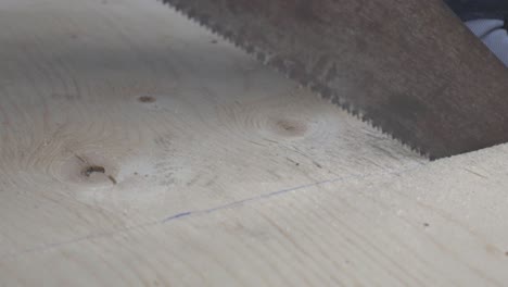 A-Person-Sawing-A-Thick-Plank-Of-Wood-With-A-Pencil-Line