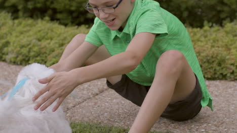 Cute-boy-plays-with-his-dog-outside-in-the-front-yard,-slow-motion