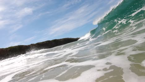 A-slow-motion-shot-from-the-water-of-a-wave-perfectly-barreling-on-a-blue-sunny-day
