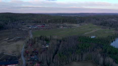 Drone-footage-slowly-orbiting-showing-a-green-golf-course-during-the-winter-while-revealing-a-small-lake