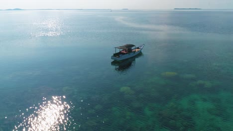 Beautiful-4K-UHD-aerial-drone-shot-of-a-tropical-Pacific-paradise-coral-reef-around-islands-in-Indonesia---Thailand---Asia-with-a-boat,-almost-no-waves,-clean,-clear-blue-water,-and-nice-sandy-beaches