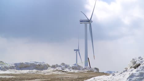 Wind-power-turbines-are-seen-in-the-half-snow-covered-ranch,-Italy