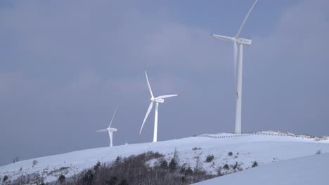 Three-windmills-are-moving-powerfully,-these-are-seen-in-the-snow-covered-mountain,-South-Korea