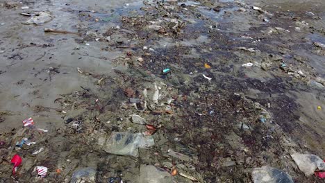 Luftaufnahme-Von-Müll-Und-Trümmern,-Die-An-Einem-Strand-Treiben