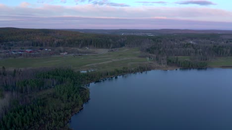 Drone-footage-slowly-orbiting-over-a-small-lake-showing-a-green-golf-course-during-the-winter