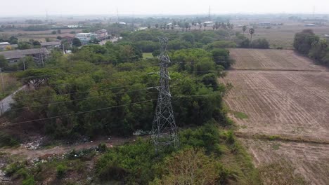 Lopburi,-Thailand---A-Tall-Tower-Mast-Surrounded-By-Lush-Green-Trees-On-The-Field---Aerial-Shot