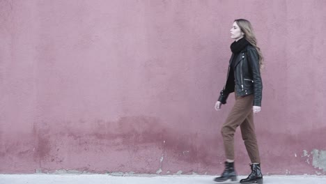 Slow-motion-video-of-a-Young-millennial-model-woman-looking-very-confident-walking-forward-wearing-modern-black-boots-and-leather-jacket-for-a-tough-look