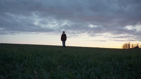 Girl-walking-through-a-field-of-grass-at-sunset
