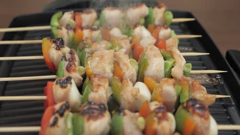 Slow-motion-shot-of-fresh-chicken-and-vegetable-skewers-cooked-on-a-electric-grill