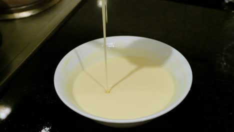 Spooning-Pancake-Mixture-in-White-Bowl,-Close-Up