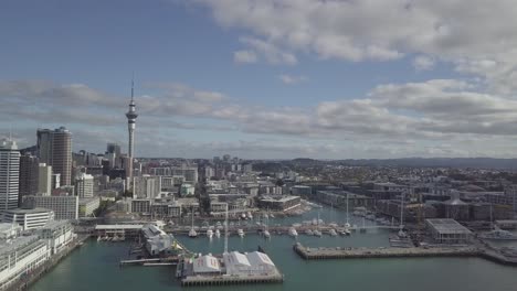 Drone-Volando-Lejos-De-Sky-Tower-Y-Mostrando-Cbd-Y-El-Puerto-De-Auckland-Queens-Wharf