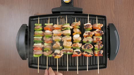 Man-cooking-chicken-and-vegetable-skewers-on-a-hot-compact-electric-grill