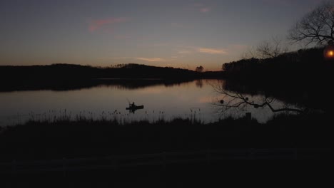drone-footage-silhouette-of-a-fisherman-on-the-lake-at-sunset