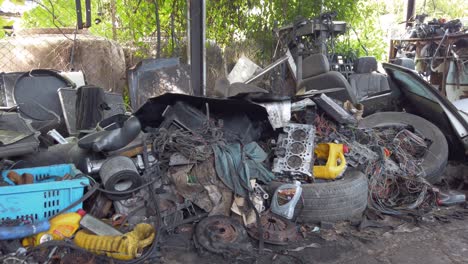Pan-shot-of-old-junk-pile-with-random-car-parts-trash-disassembled-on-ground