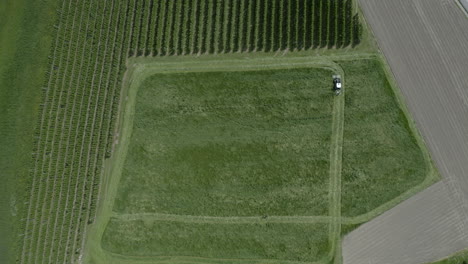 Tractor-with-mower-working-on-large-grass-field,-farmland-aerial-view