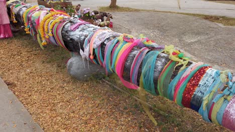 Colorful-Ribbons-Tied-Around-A-Tree-Log---Tradition-And-Beliefs-In-Thailand---Closeup,-Slider-Shot