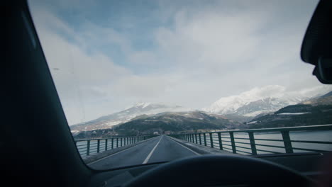 Tranquil-mountain-scenery-from-inside-of-a-car-driving-on-lake-bridge