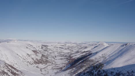 View-of-a-snow-covered-valley-in-the-Cantal-mountains,-pan-form-right-to-left