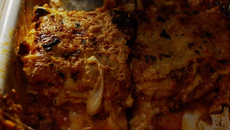 Cutting-and-serving-a-portion-of-a-delicious-meat-lasagne-with-grated-cheese