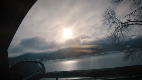 View-from-car-side-window-on-lake-and-mountains-backlit-by-sun-slow-motion-drive