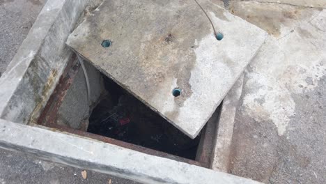 Open-Manhole-With-Rubbish-Stagnant-Water---Concrete-Cover-Removed---high-angle-shot