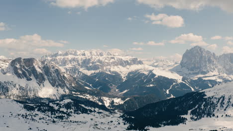 Aerial-panoramic-view-of-Dolomites,-jagged-mountain-tops-in-snow