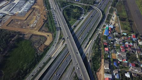 Scenic-aerial-view-above-busy-highway-intersection-ramp-with-traffic-in-industrial-area