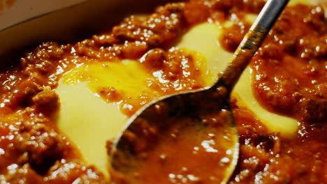 Detail-close-up-of-spoon-spreading-meat-tomato-sauce,-cooking-lasagne-process