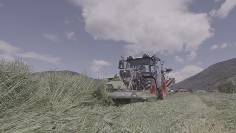 Tractor-mowing-grass-in-meadow,-modern-automated-agriculture-equipment