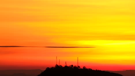 Slow-tilt-down-on-silhouette-of-radio-communications-towers-against-vibrant-orange-sunset