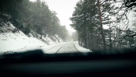 Car-drive-forest-road-during-snow-fall-windshield-view-in-slow-motion