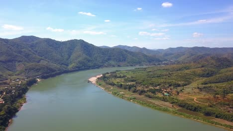 Pristine-View-Of-Famous-Mekong-River-Surrounded-By-Lush-Green-Valleys-And-Mountains-Under-Summer-Blue-Sky---Aerial-Drone-Wide-Shot