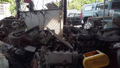 Junk-car-parts-and-metal-plastic-machine-material-scrap-piled-against-chain-link-fence